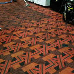 Red and black patterned carpet in an arcade or entertainment venue, with machines partially visible on the sides.