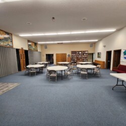 Multipurpose room with round tables and chairs, bookshelf, wall art, and a banner reading "Receptive United Methodist Church.